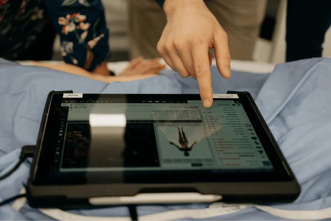 Doctor pointing at medical tablet screen displaying patient data.