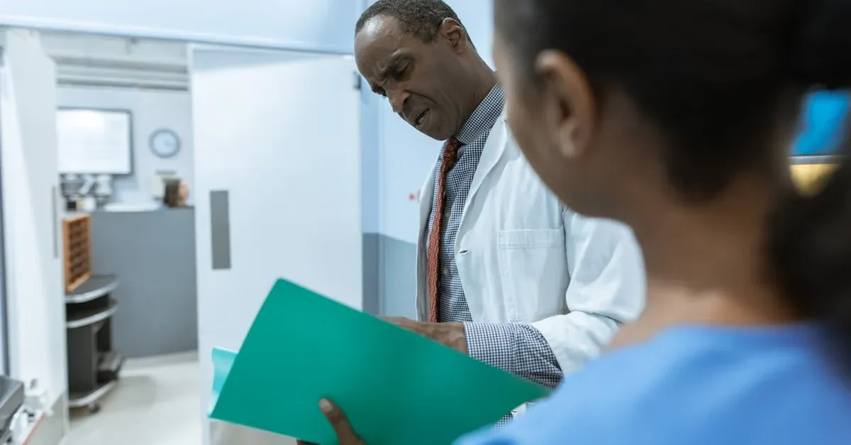 Doctor reviewing green medical chart with colleague in hospital facility.