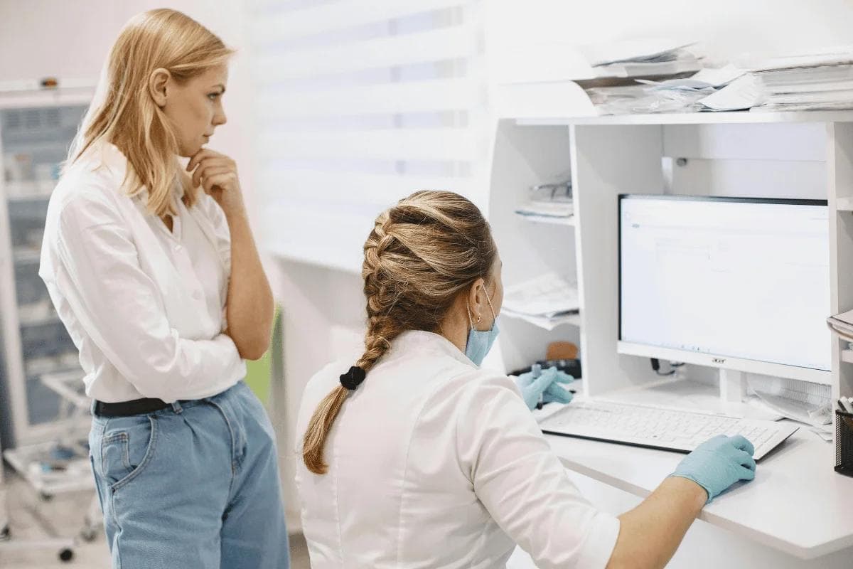 Doctor showing medical data on computer to patient.