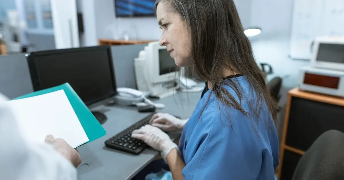 Healthcare worker reviewing patient data on tablet in clinical workspace.