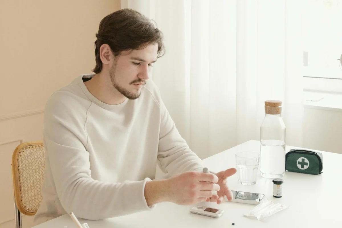 Man checking blood sugar levels at home with glucose meter.