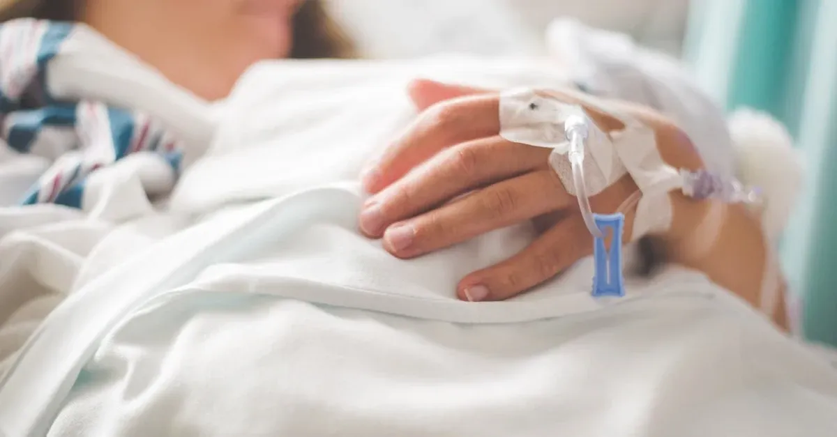 Patient's hand with IV line and medical monitor clip during hospital care reducing hospital readmissions through monitoring.