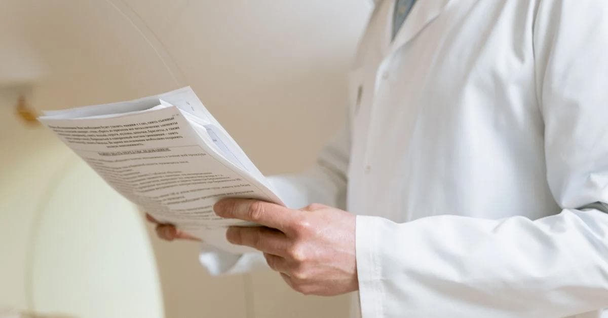 Healthcare professional reviewing ACO Reach program documentation guidelines on clipboard form.