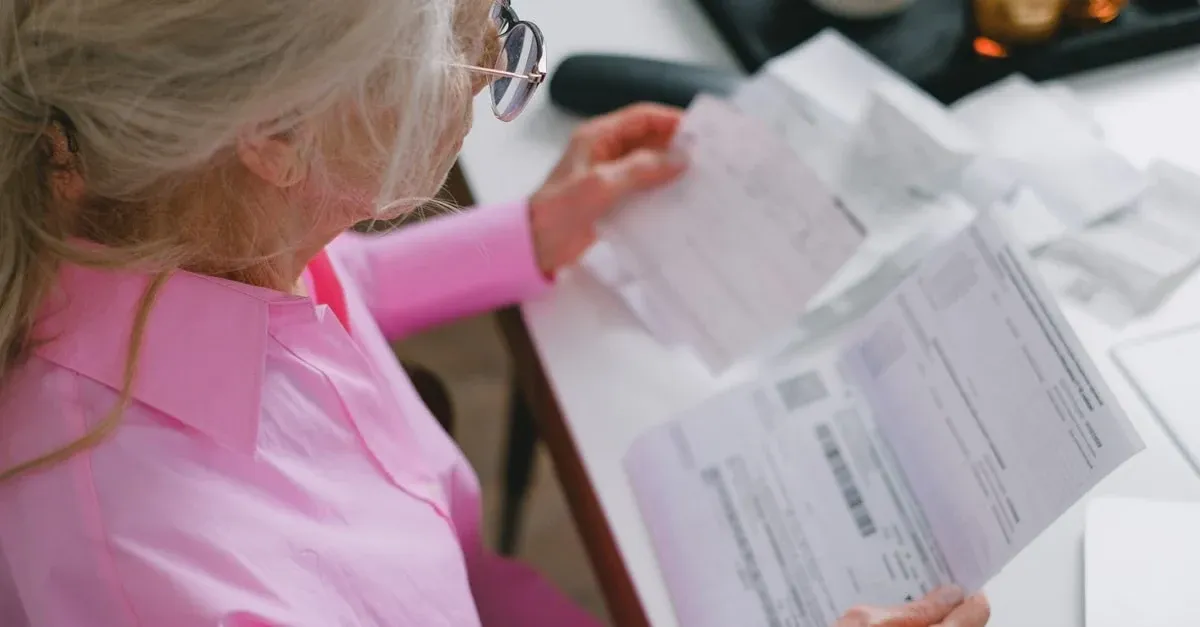 Older woman in pink shirt reviewing healthcare documentation comparing APCM vs CCM options at table.