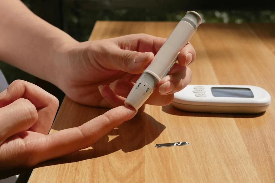 Person pricking finger with lancing device for blood sugar test.