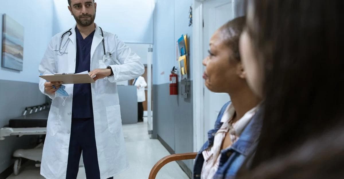 Doctor in white coat consulting with patients in clinic about Medicare guide program benefit.
