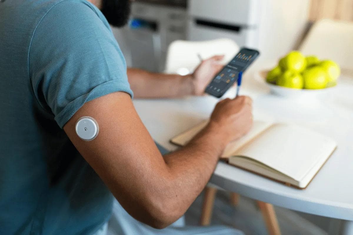 Person using continuous glucose monitor and mobile app.