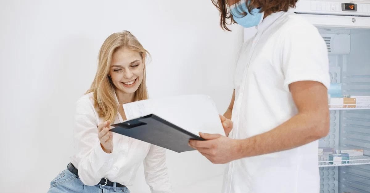 Male healthcare provider showing female patient remote patient monitoring heart failure data on digital tablet.