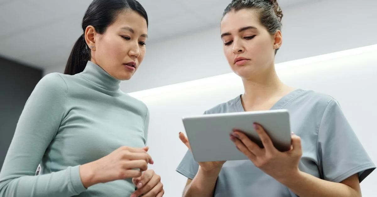 Healthcare provider discussing remote patient monitoring heart failure data on tablet with patient in clinic.
