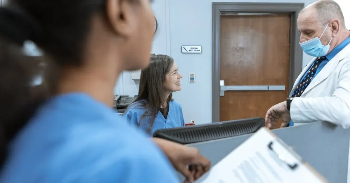Doctor in mask discusses APCM vs CCM options with patients at clinic reception desk.