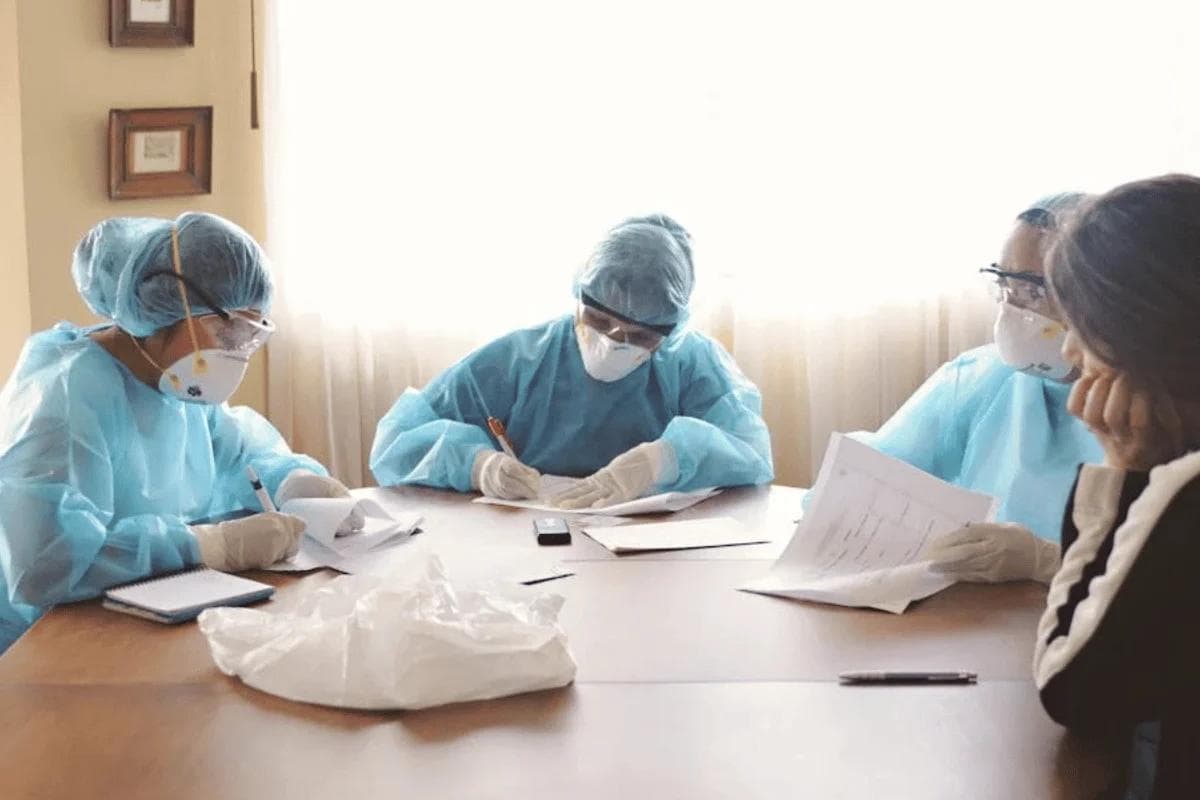 Healthcare professionals in scrubs discussing fee for service vs value based care payment models around conference table.