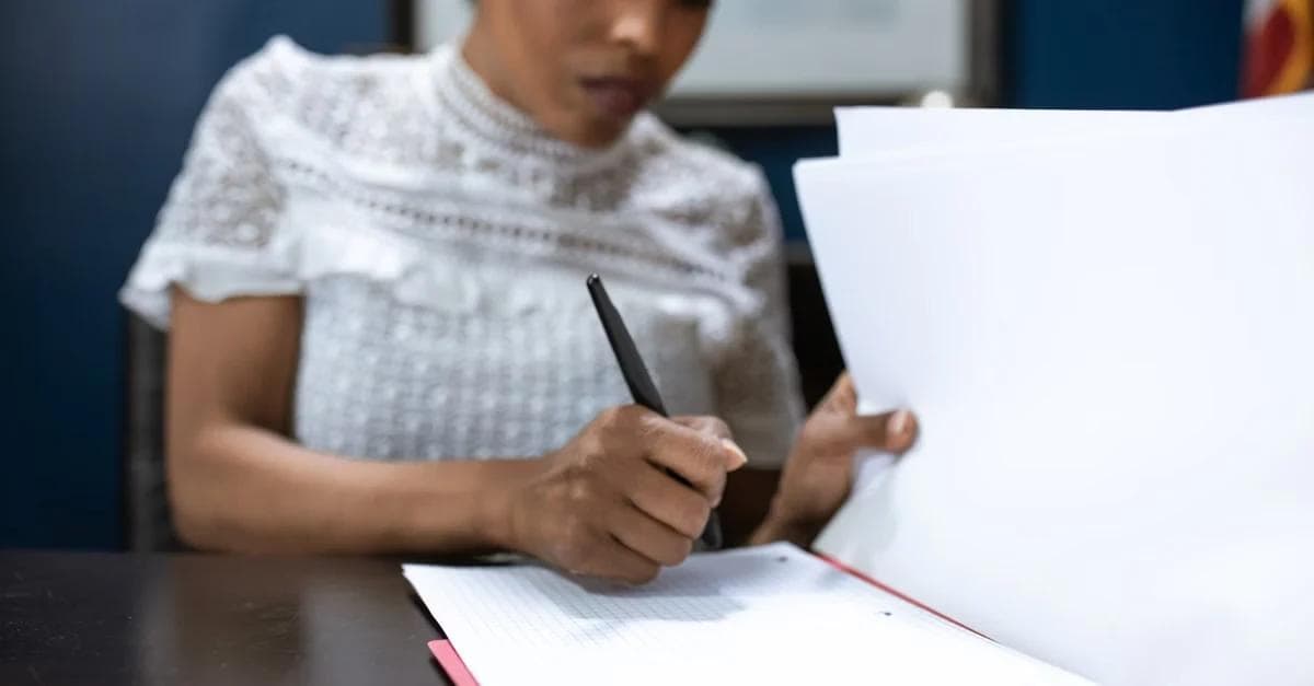 A lady writing on document at desk demonstrating chronic care management eligibility requirements and patient engagement.