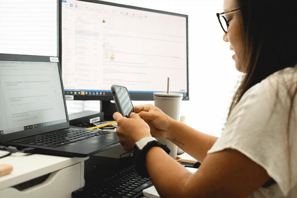 Professional working with two monitors and smartphone.