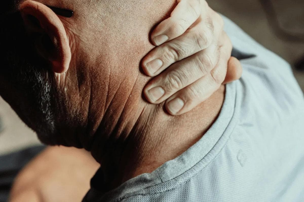 Person holding the back of their neck in discomfort.