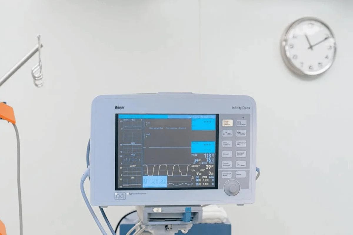 Medical monitor displaying patient data supporting fee for service vs value based care payment models in hospital room.