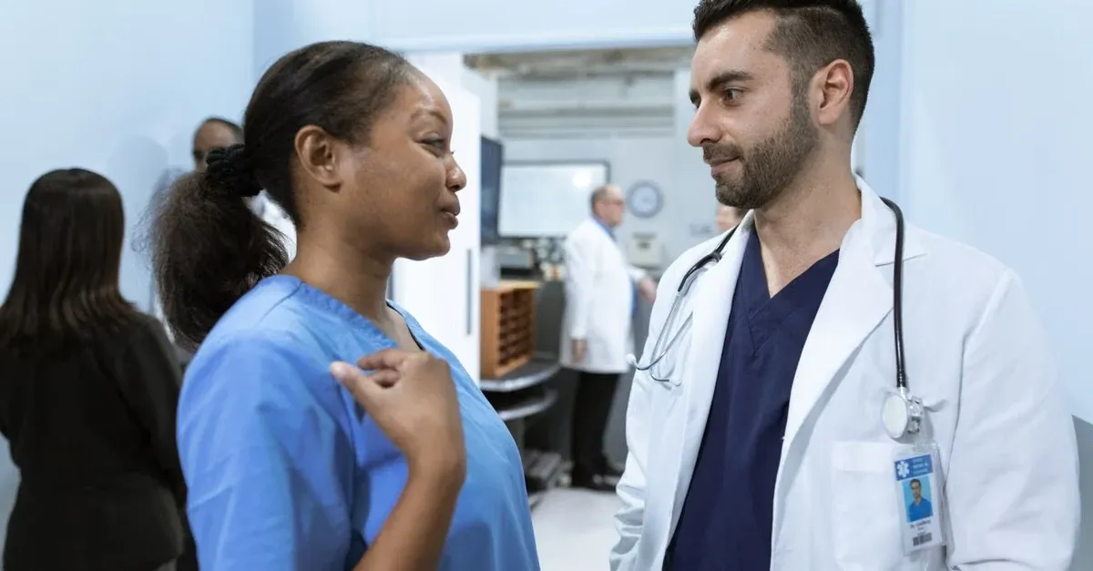 Doctor in white coat discussing patient care with nurse in healthcare clinic setting.